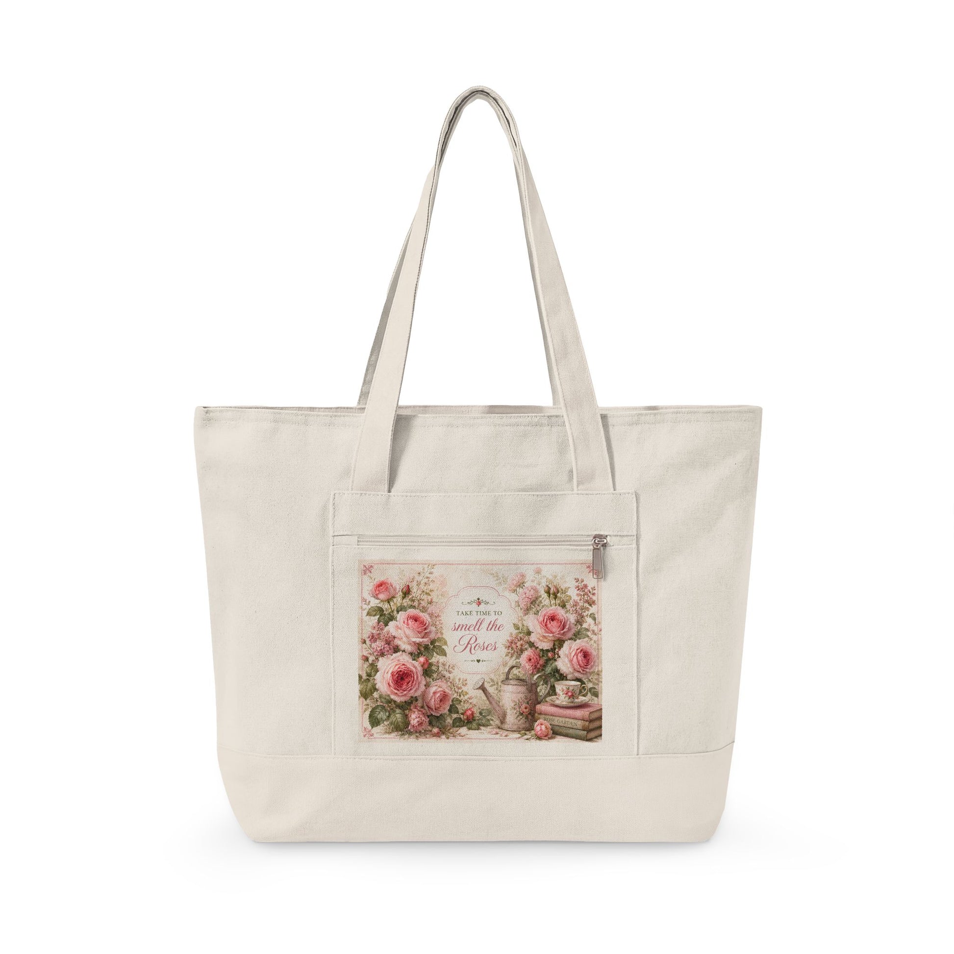 An off-white canvas tote bag with dual shoulder straps and a front zippered pocket featuring a vintage-style floral print with pink roses and cursive text.